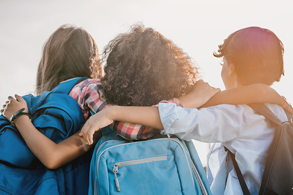 Students embrace while wearing backpacks